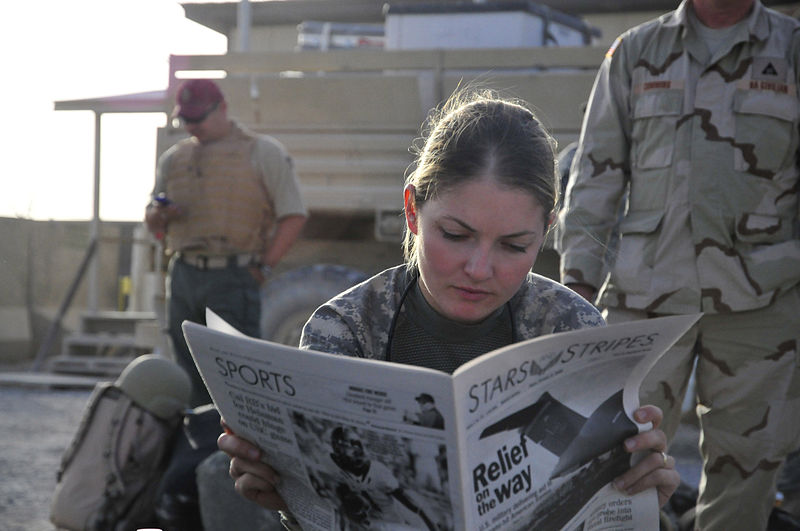 Mulher lendo jornal.